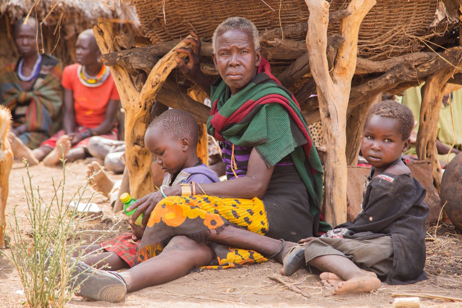 A mother sitting with her children outside a rural home.